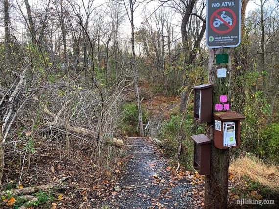 Trail markers and map boxes on a wooden post at the Sierra Trailhead.