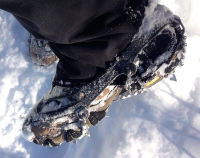Hiker wearing microspikes traction on an icy trail.