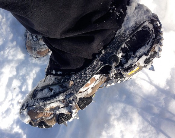 Side of hiking boot showing snow covered microspikes.