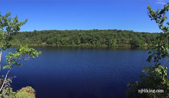 Beyond bright blue Surprise Lake is a hill covered in green trees