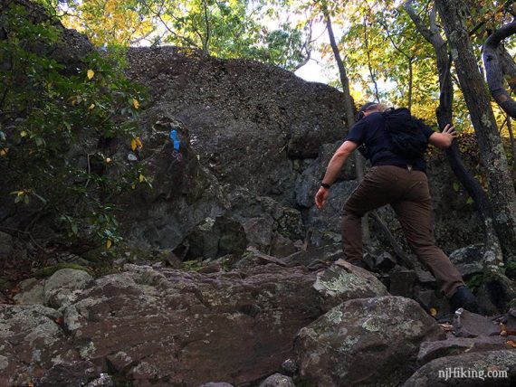 Hiker scrambling over a rocky trail.