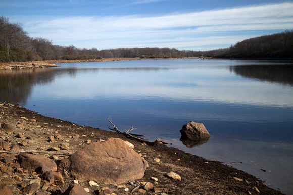 Flat blue water of a reservoir seen from the shore edge.