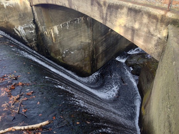 Looking down at water flowing down a concrete dam.