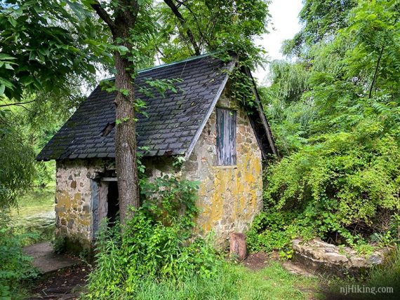 Small stone building and well next to a pond.