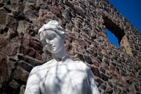 Female statue against a brick wall.