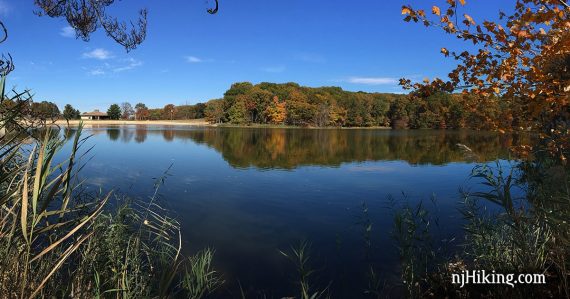 Blue lake with fall foliage reflected in it.