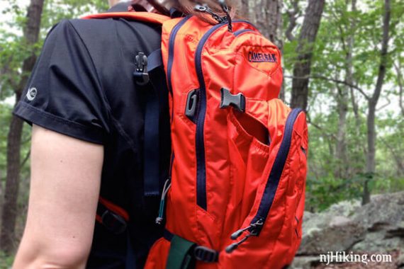 Hiker wearing a bright orange Camelbak M.U.L.E. backpack.