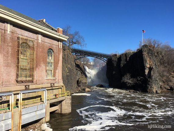 Bridge over Paterson Falls with a building and river in the foreground.
