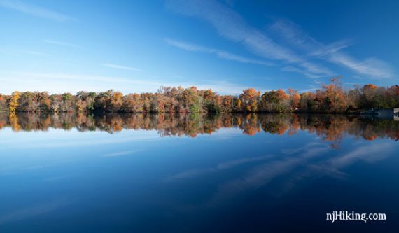 Bright blue Parvin Lake with a line of autumn trees