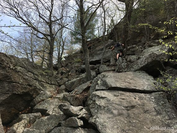 Hiker climbing up a steep rocky hill.
