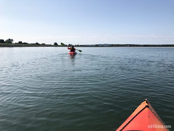 Kayker paddling a flat blue lake.