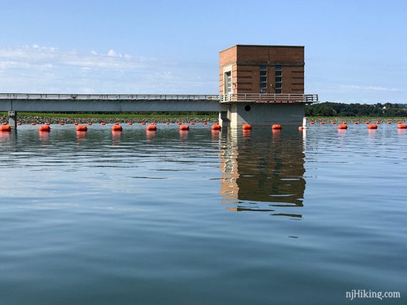 Tower in a lake with a rope of buoys around it.