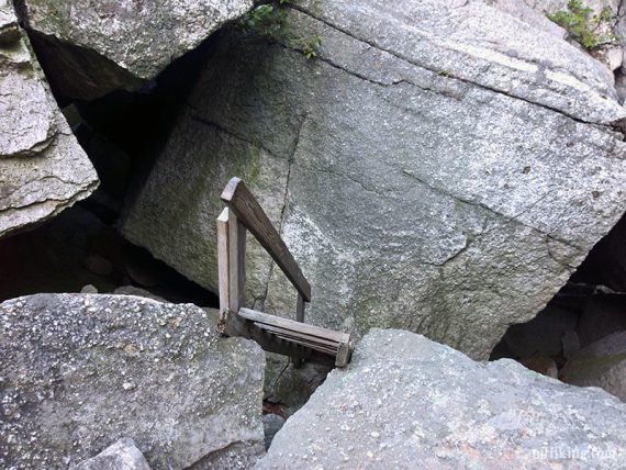Wooden ladder assisting a climb down a jumble of large boulders.