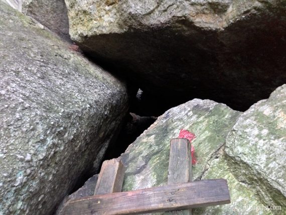 Looking into a tight rock crevice from the top of a ladder.