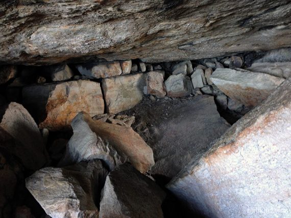 Looking into a cave with a flat rock overhang.