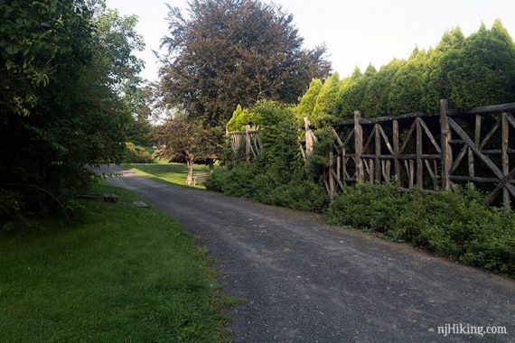 Gravel path with a criss cross wooden fence along it.