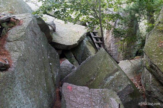 A labyrinth of large angled rocks with a ladder on them.