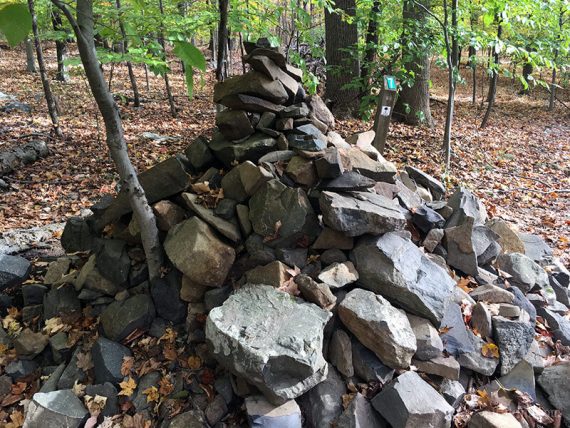 Rocks stacked in a large pile on a trail.