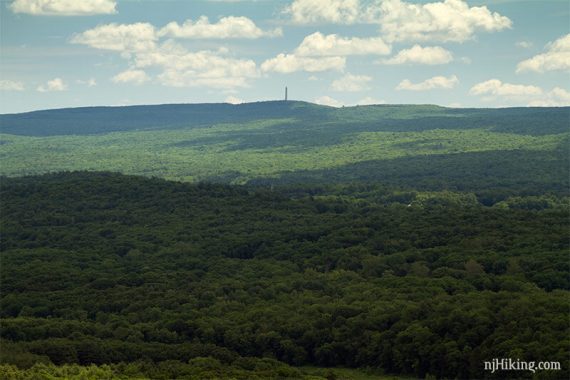 Zoom into High Point Monument on a hill above forested hill sides.