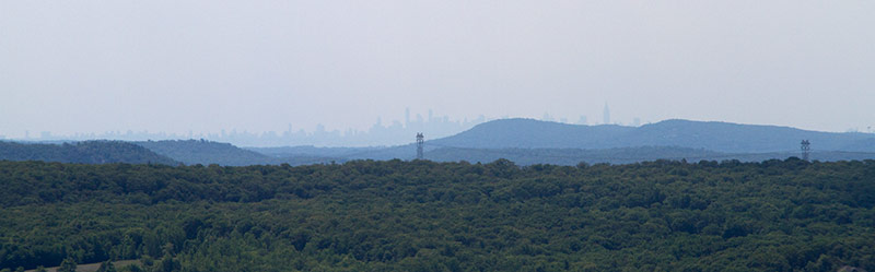 New York City skyline seen in the far distance from a viewpoint.