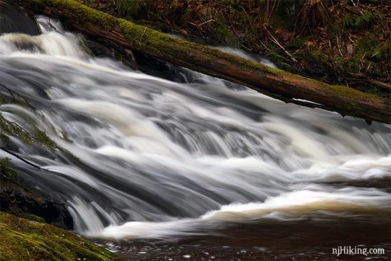 Close up of a waterfall cascading over an angled rock.