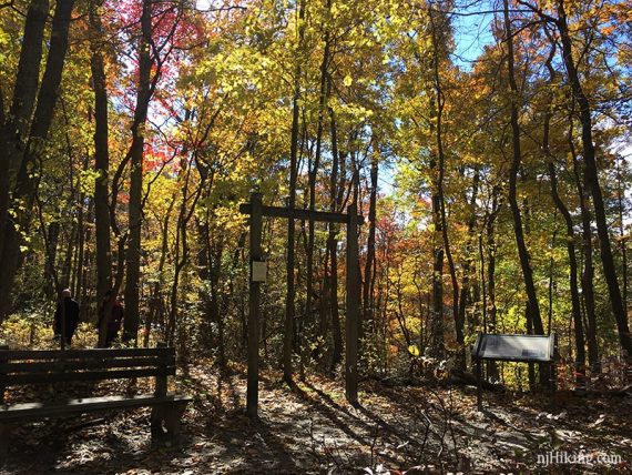 Bench, wooden trail arch and sign at an intersection.