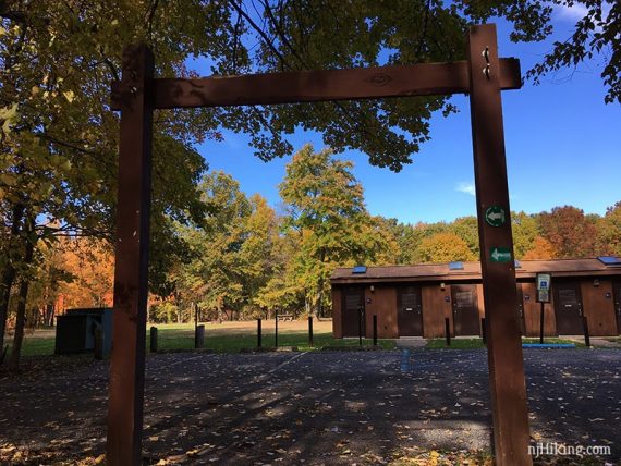 Wooden trail arch with park restrooms beyond.