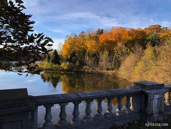 Bright foliage reflected in water with a stone railing in the foreground.