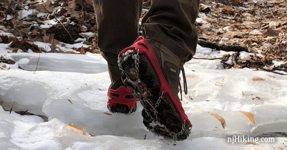Hiker wearing microspikes traction on an icy trail.