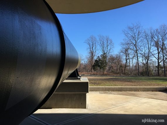 Inside a bunker and looking out alongside a large gun barrel.