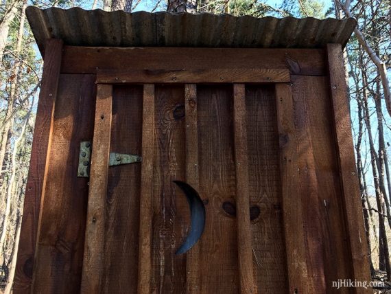 Wooden outhouse door with a half moon carved into it