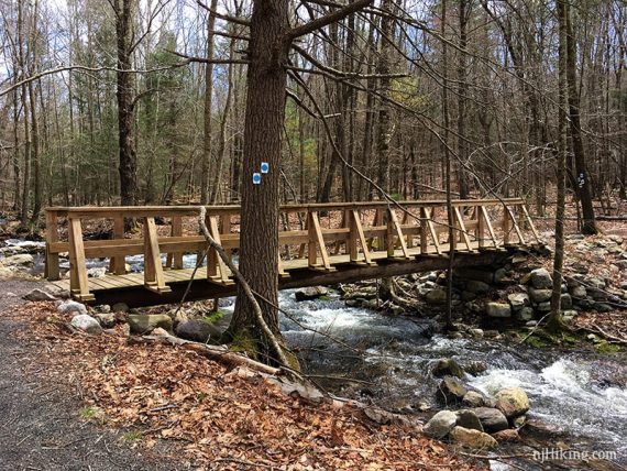 Long wooden trail bridge over stream.