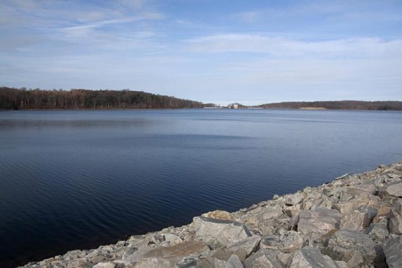 Bright blue reservoir near a stone wall.