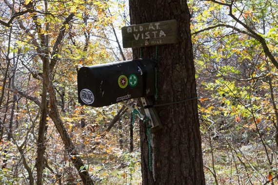 Old A.T. Vista sign and sticker covered mailbox on a tree 