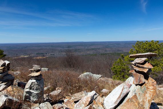 Stacked rocks in the foreground with a wide view over a valley.