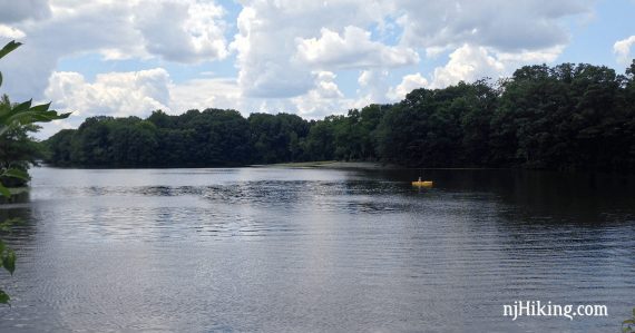 Kayak on a blue lake with green trees along the shore of Farrington Lake.