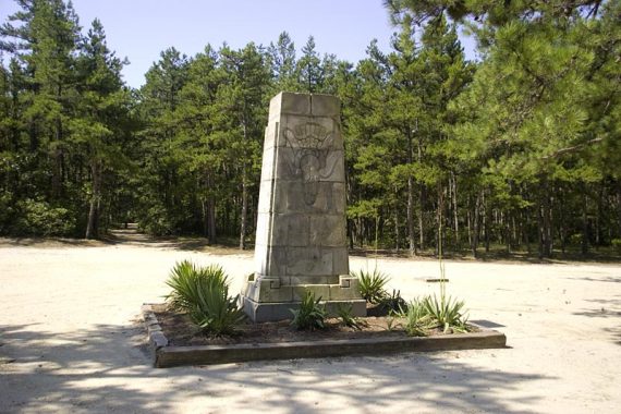 Carranza Memorial surrounded by green plants in a sandy parking area.