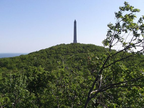High Point Monument obelisk on a green forested hill