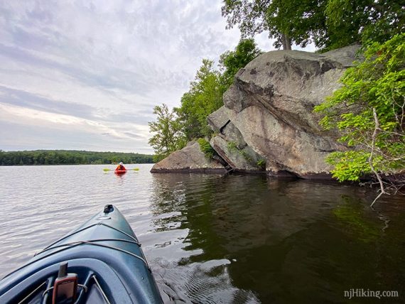 Tall rock face at the shore of a lake with two kayaks.
