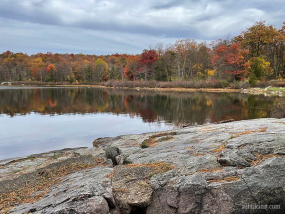 Rocky outcrop next to a lake with just past peak fall foliage.