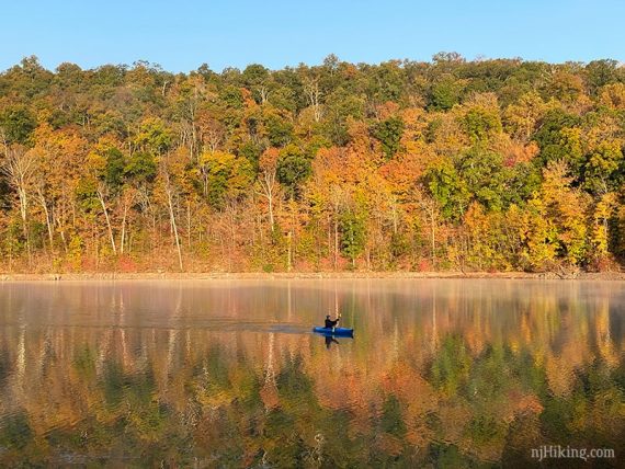 Kayaker with fall foliage reflected in the water