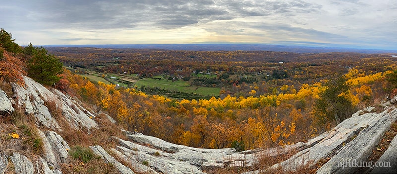 Panoramic view from a rock ridge of foliage and farms below.