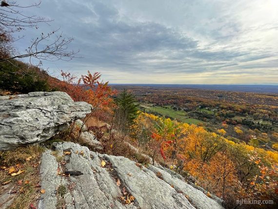 Rock jutting out on a ridge overlooking farms and bright foliage.