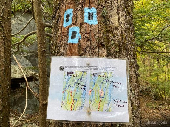 Trail sign and blazes on a tree.