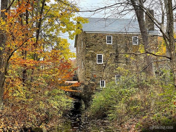 Cooper Mill with a stream in front and surrounded by fall color.