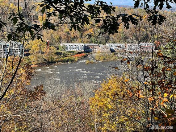 Long white building see through the trees on the other side of a river.