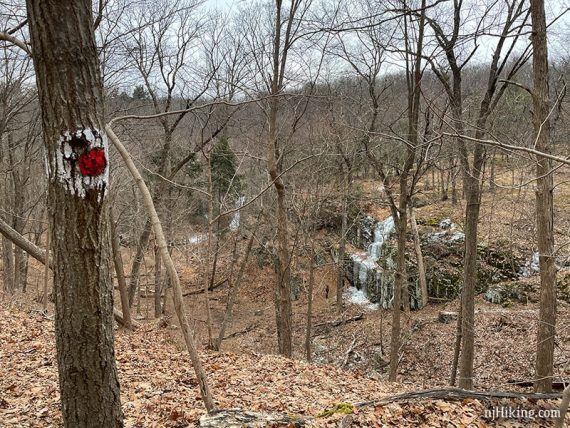 Red dot on white trail marker in the foreground with ice cascades in the distance.