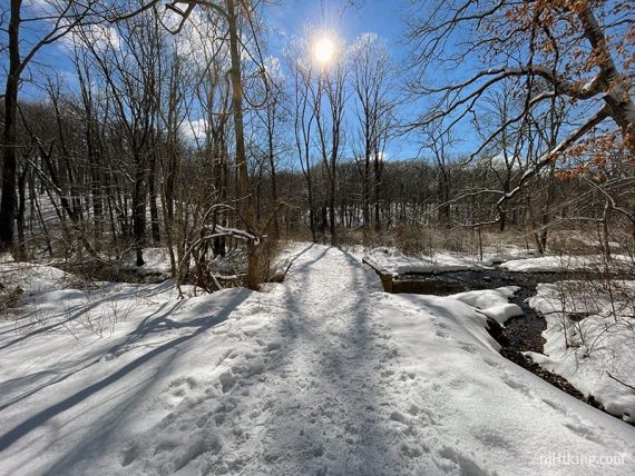 Packed snowy trail and bridge over stream