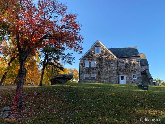 Stone park building next to a red tree.