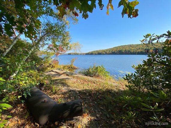 Open area near a lake with cement and a large pipe.